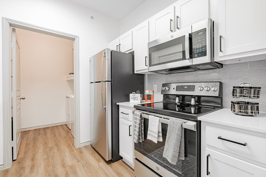 a kitchen with white cabinets and stainless steel appliances and a refrigerator