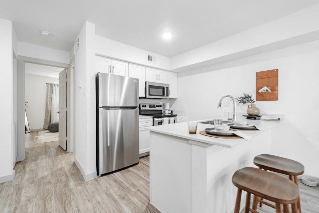 A modern kitchen with a white refrigerator, stove, and bar stool.