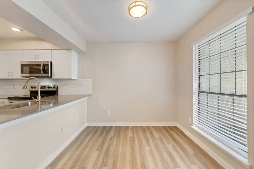 a kitchen with white cabinets and a large window