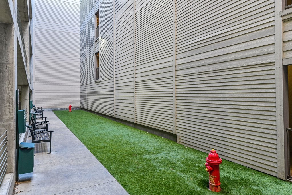 A red fire hydrant sits on a green lawn next to a building.
