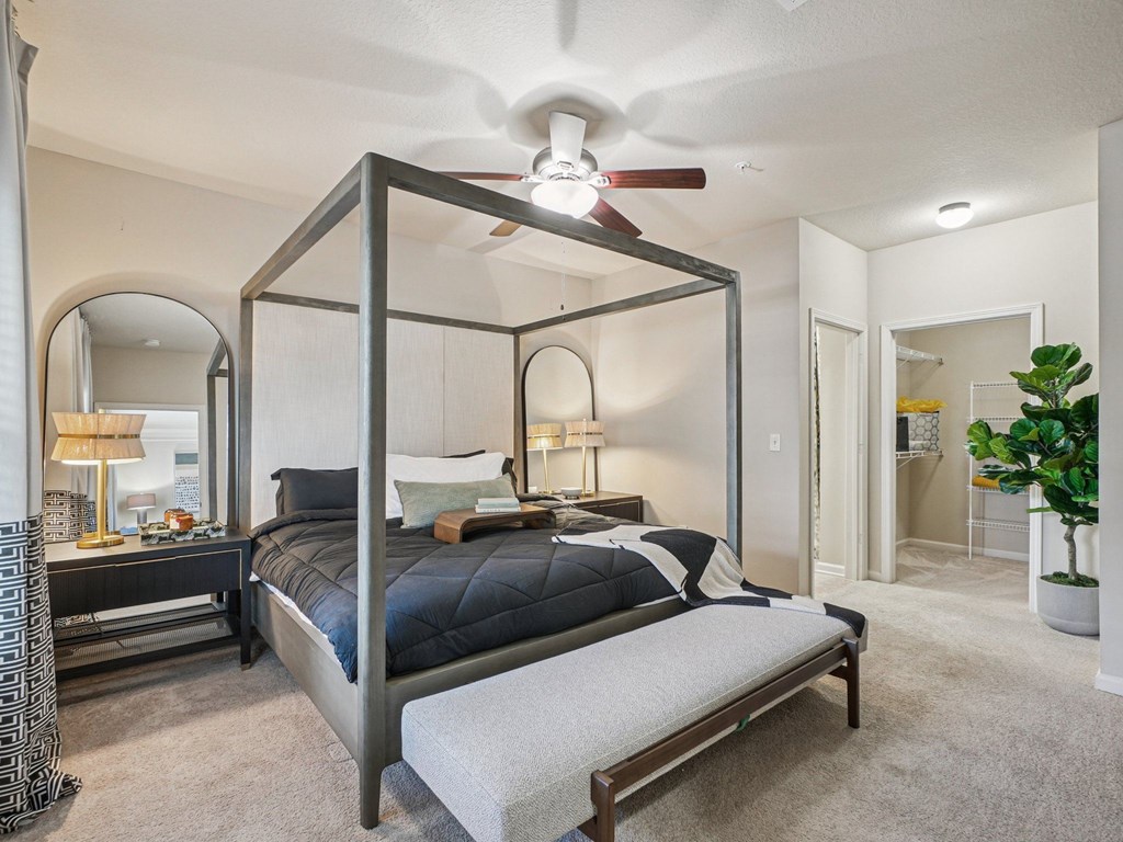 A bedroom with a four poster bed and a ceiling fan.