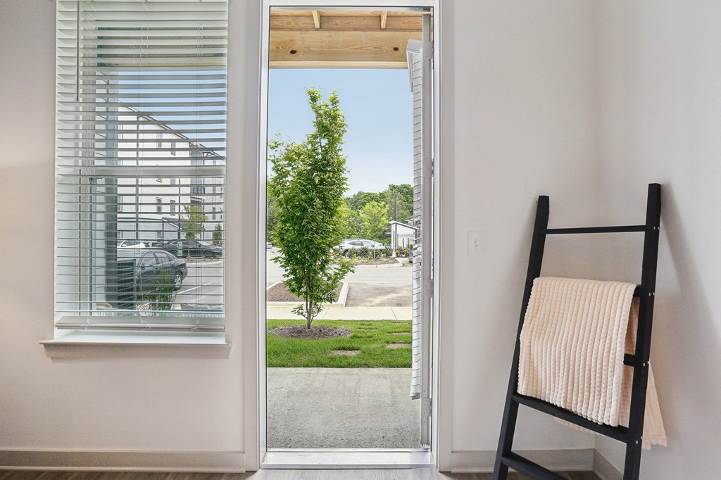 A room with a ladder and a window overlooking a yard.
