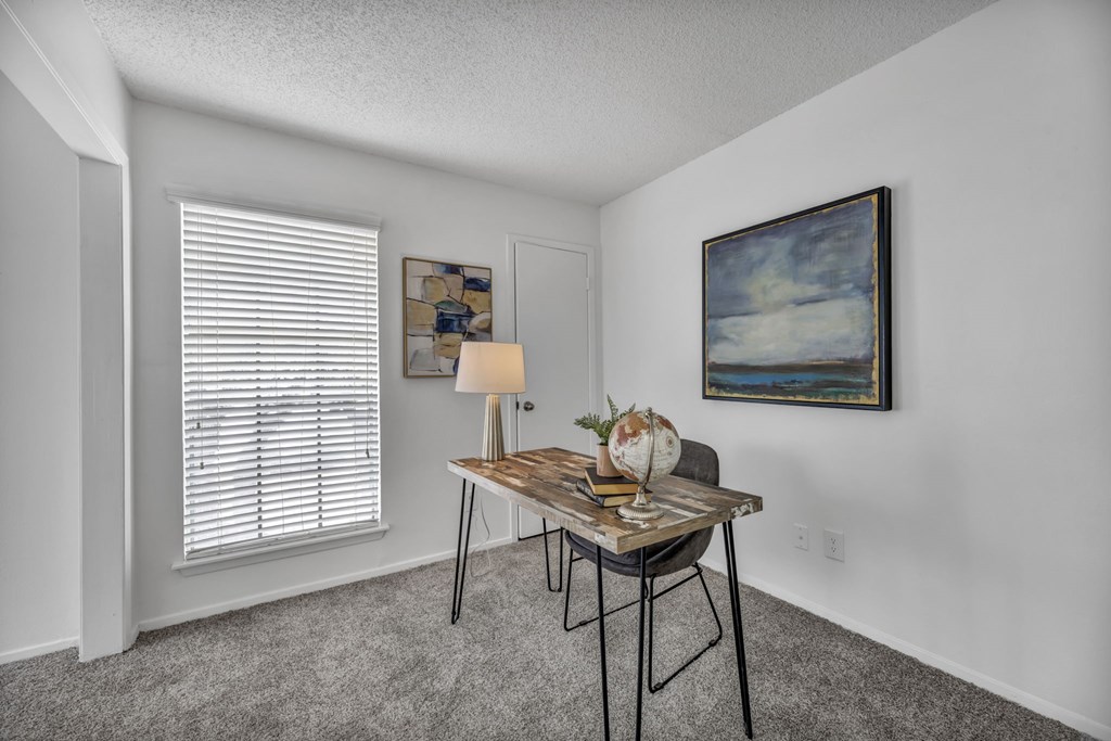 A room with a table, chairs, and a painting on the wall.