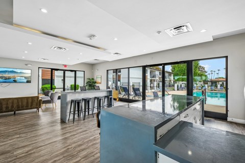 A modern room with a bar and a pool outside.