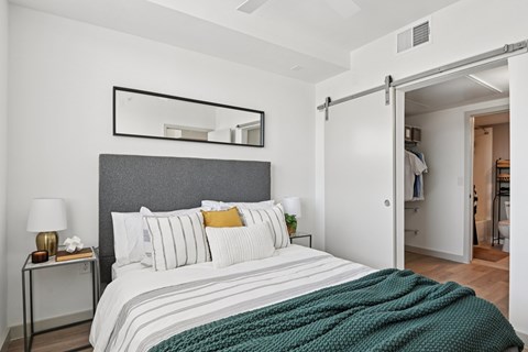 A bedroom with a bed, nightstand, and a mirror above the bed.