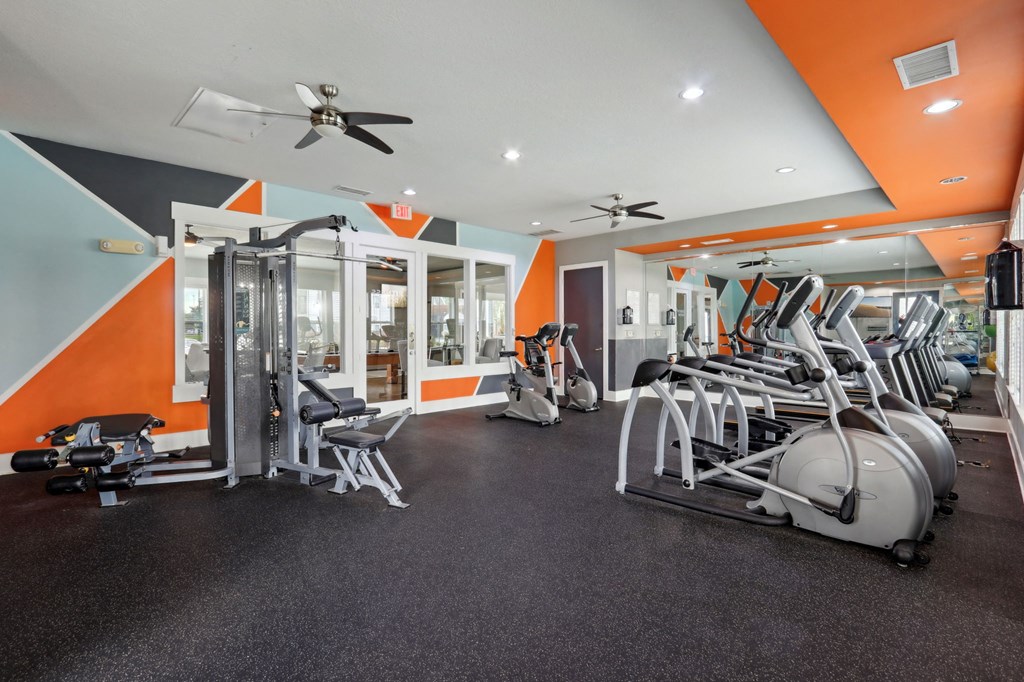 A gym with orange walls and a variety of equipment.