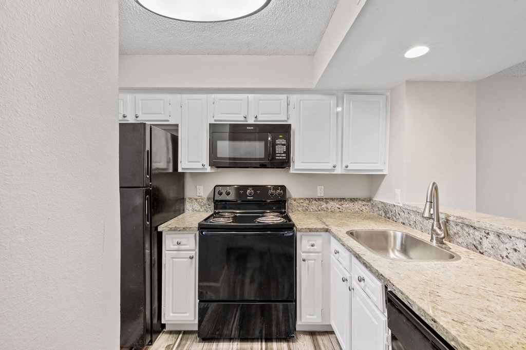 A black stove and oven in a kitchen with white cabinets.