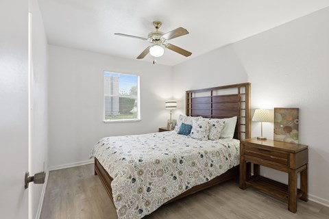 A bedroom with a bed, nightstand, and window.