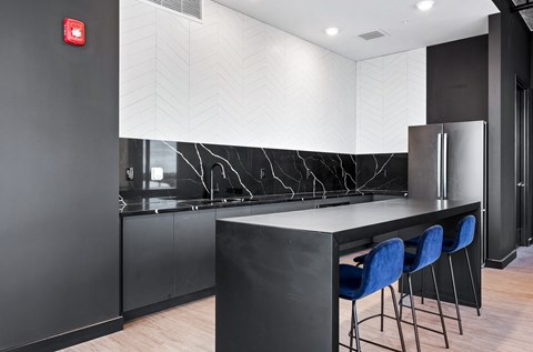 a kitchen with black cabinets and a counter with blue chairs