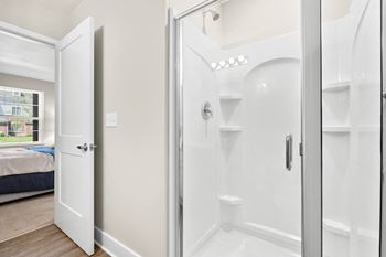 a bathroom with a shower and a bed in a room