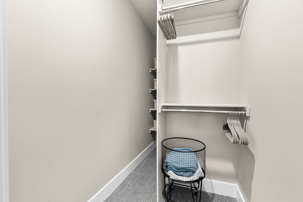 a walk in closet with a wicker basket and a shelf with folded towels