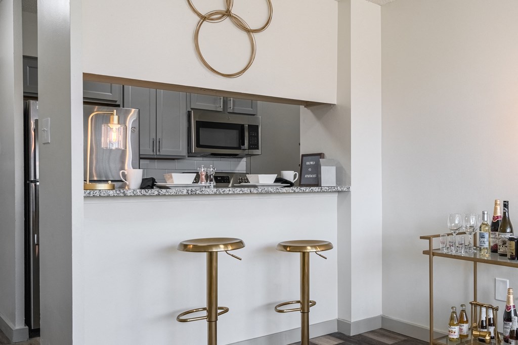 a kitchen with stools and a counter with a sink and a microwave