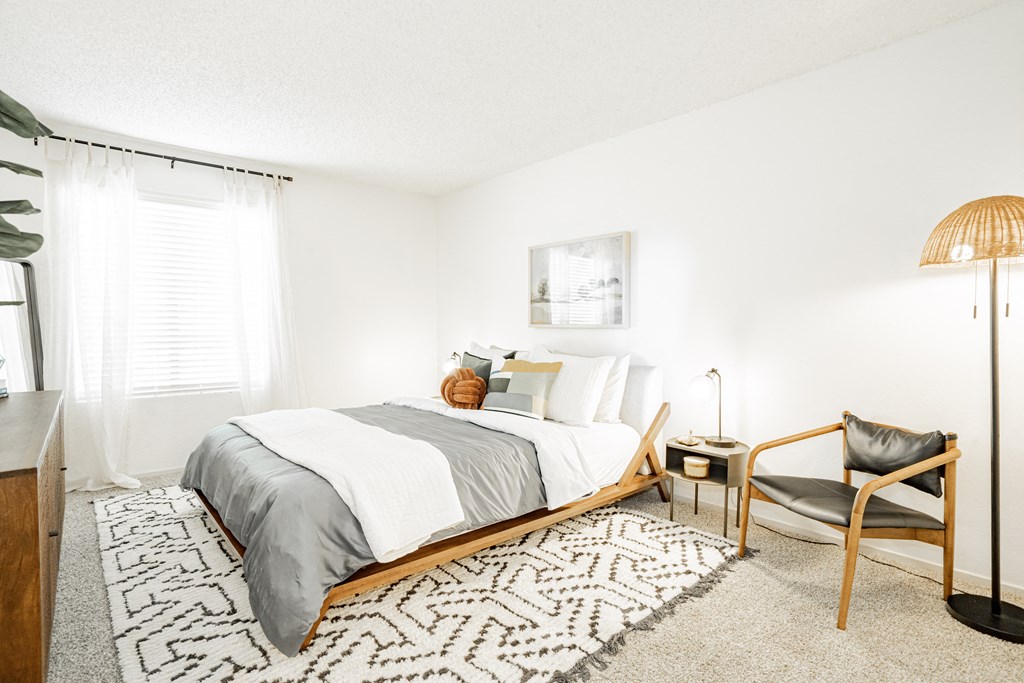 a bedroom with a bed and a chair and a rug