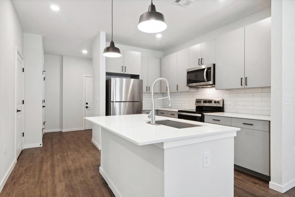 a white kitchen with a large island and stainless steel appliances