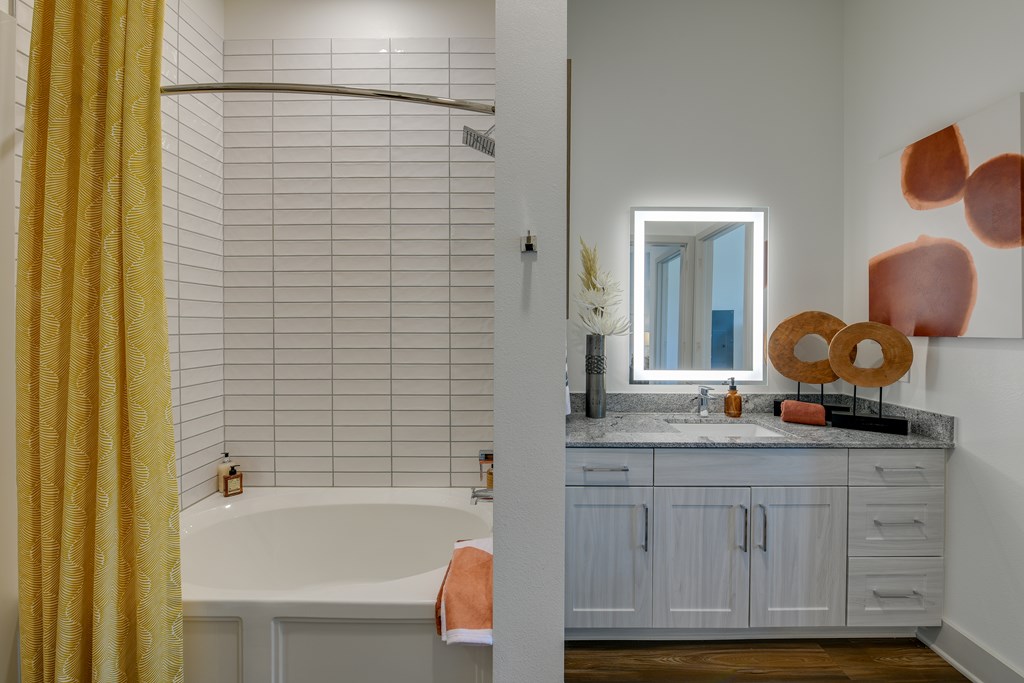 A bathroom with a yellow shower curtain and a white bathtub.