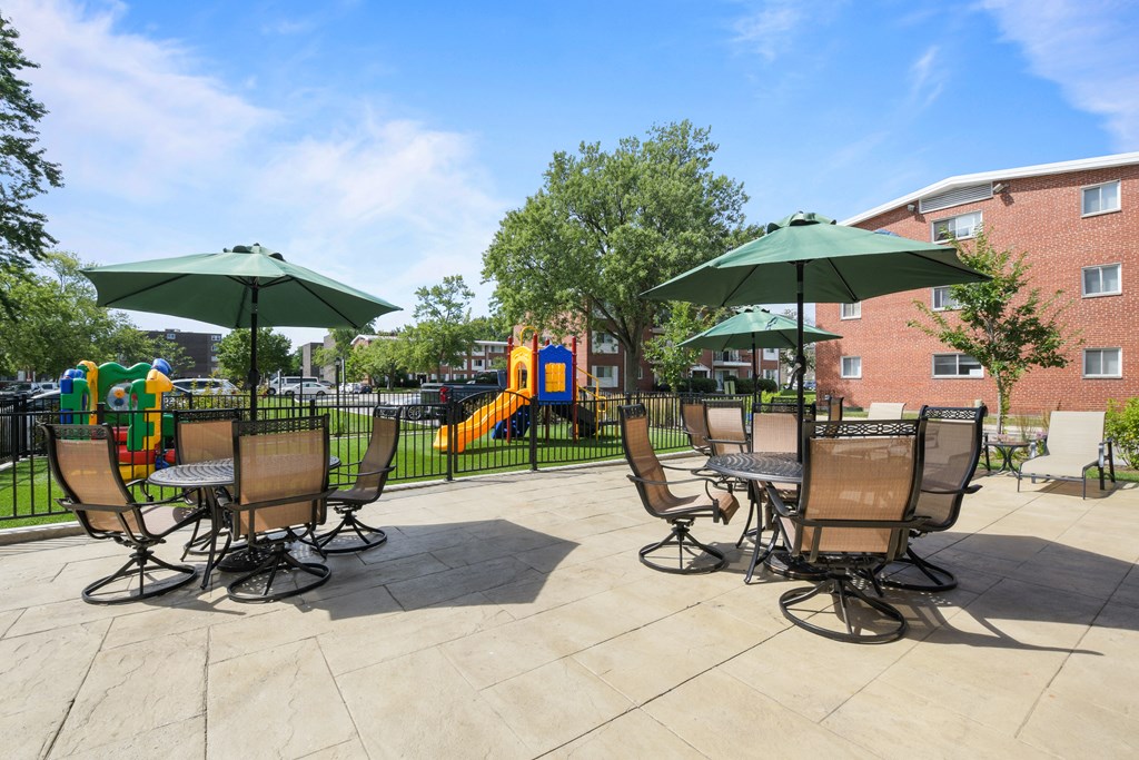 an outdoor patio with chairs and umbrellas and a playground