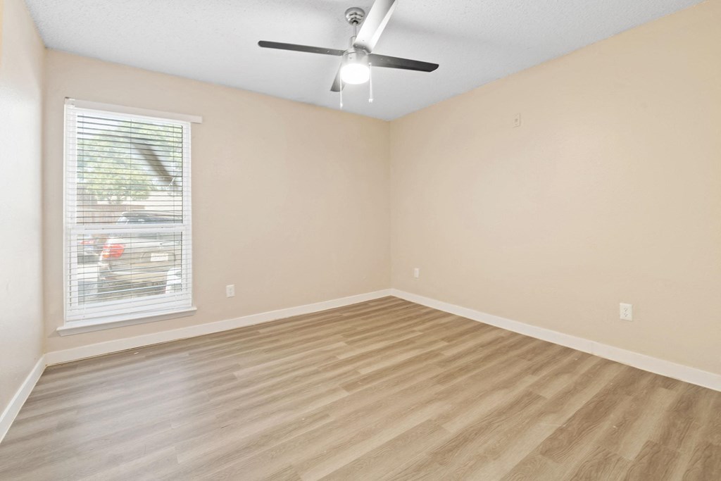 an empty living room with a ceiling fan and a window