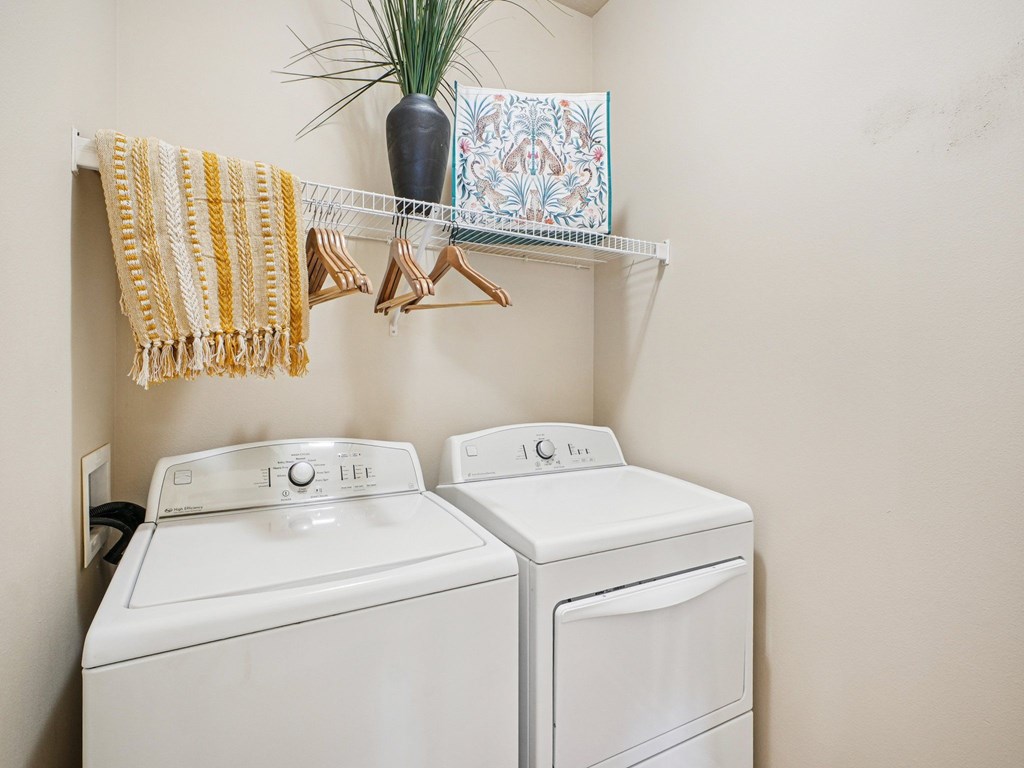 Two white washing machines in a laundry room.