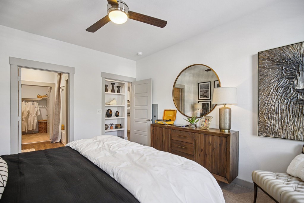 A bedroom with a bed, dresser, mirror, and a painting on the wall.