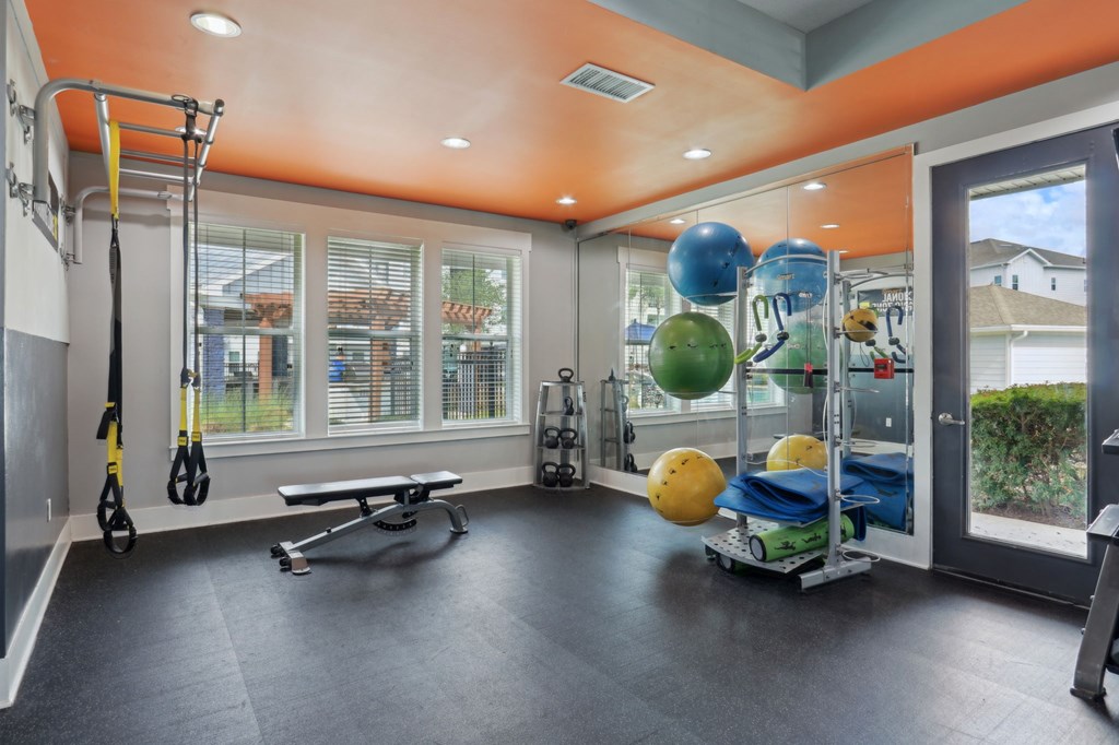 A gym with a bench, weights, and exercise equipment.