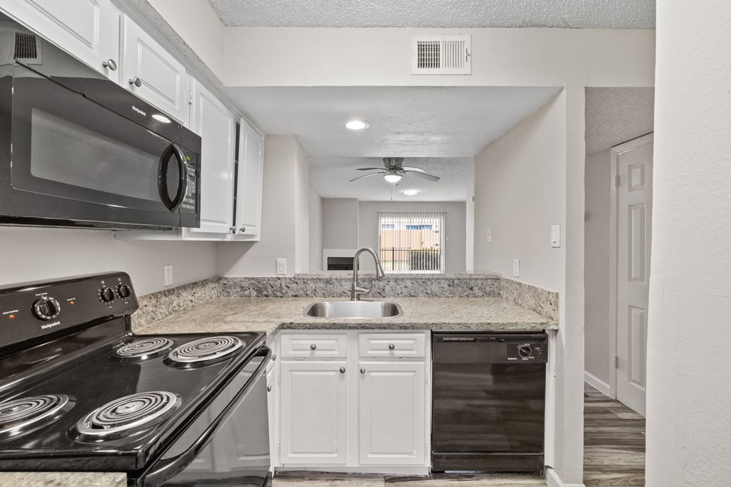 A kitchen with a black stove top oven and white cabinets.