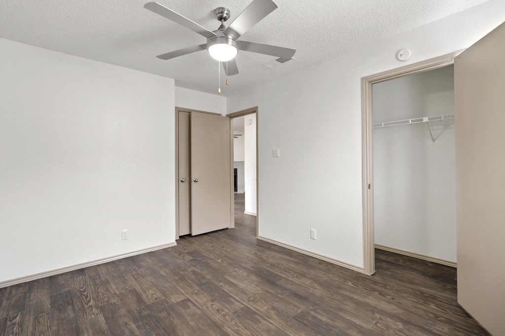 A room with a ceiling fan and wood flooring.