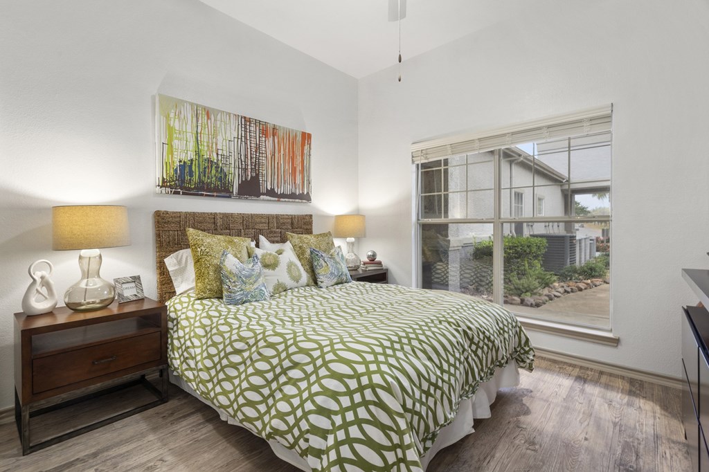 A bedroom with a bed, nightstand, and a painting on the wall.