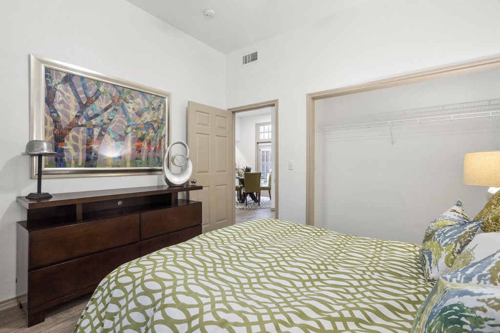 A bedroom with a bed, a dresser, and a painting on the wall.