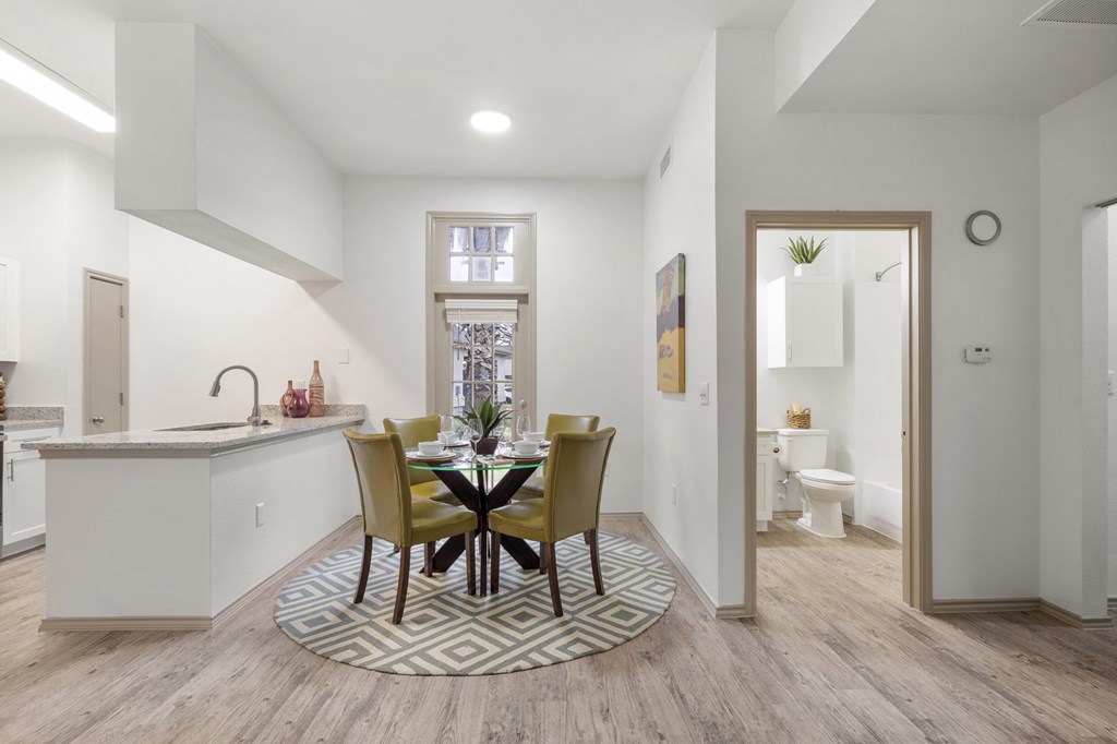 A kitchen with a dining table and chairs in the middle.