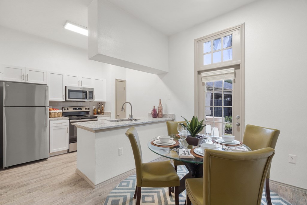 A kitchen with a table set for two with a window in the background.