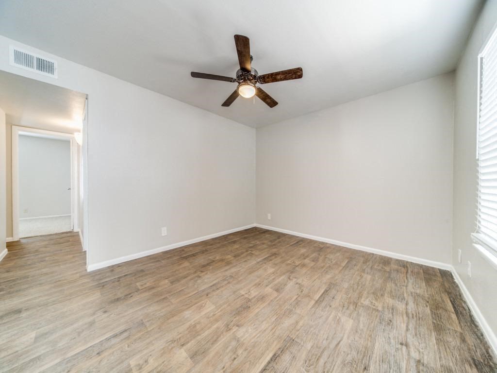 an empty living room with wood flooring and a ceiling fan