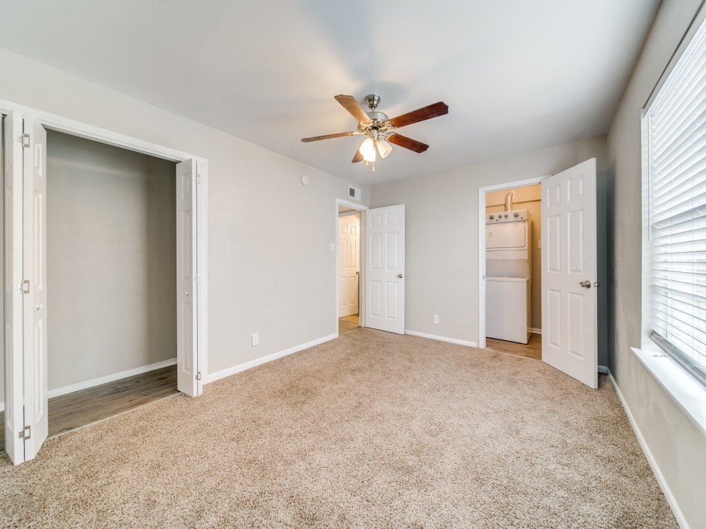 an empty living room with a ceiling fan and a closet