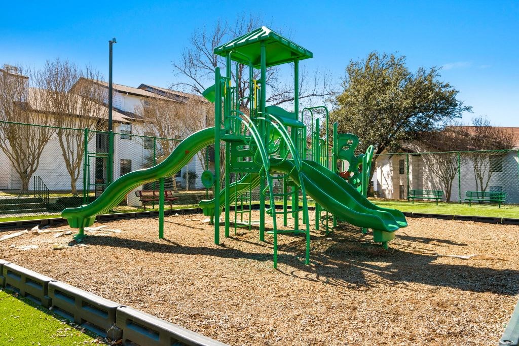 a playground with a green playset in a park