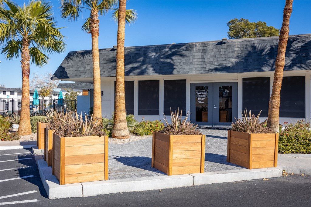 a building with a gray roof and palm trees in front of it