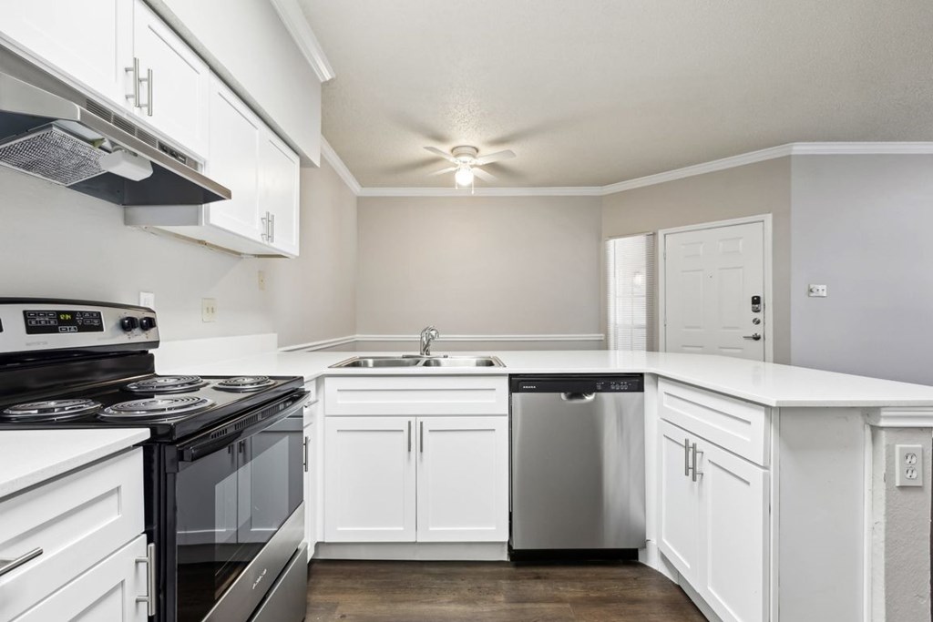 A modern kitchen with white cabinets and a black stove top.