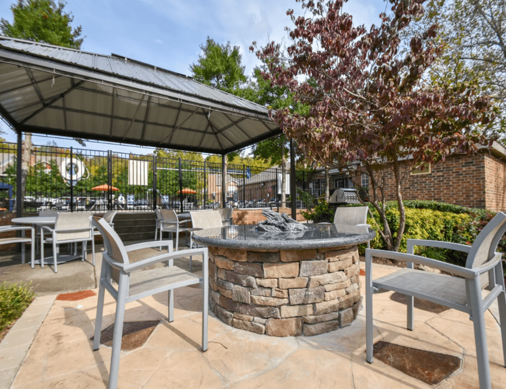 a patio with tables and chairs and a fire pit