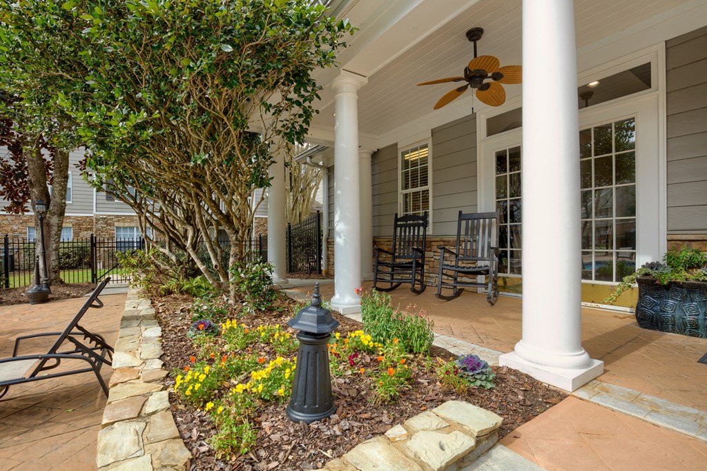 the front porch of a house with benches and a garden