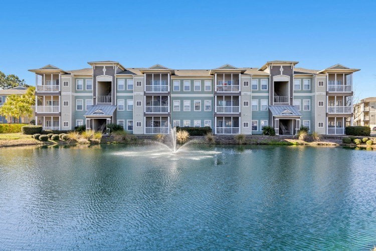 an apartment building overlooking a lake with a fountain