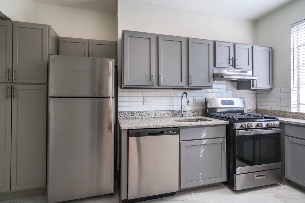 an empty kitchen with stainless steel appliances and gray cabinets