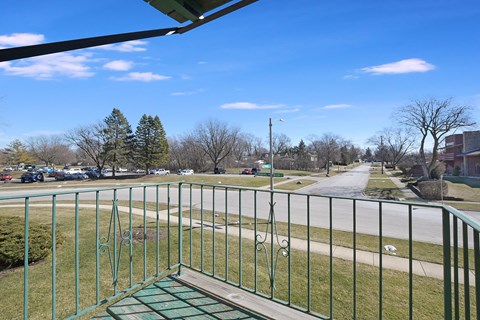 a view of a park from a balcony with a metal fence