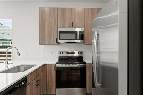 A modern kitchen with a stainless steel refrigerator, microwave, and oven.