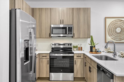 A modern kitchen with a refrigerator, microwave, oven, and sink.