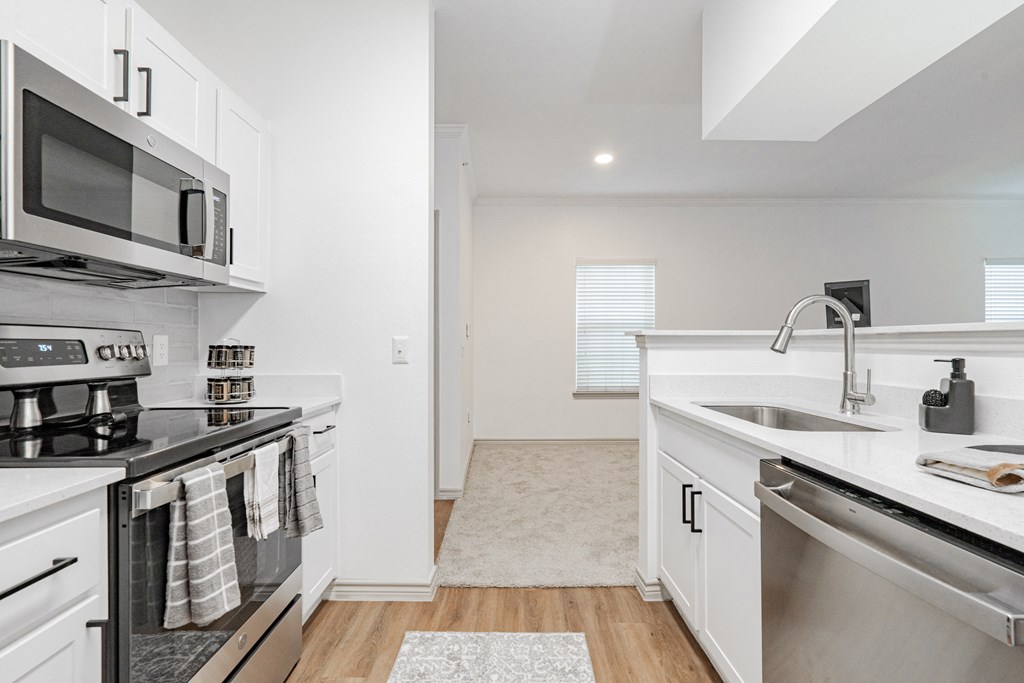 a renovated kitchen with stainless steel appliances and white cabinets