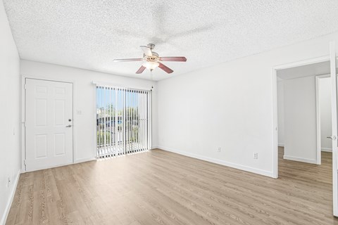A room with a ceiling fan and sliding glass doors.