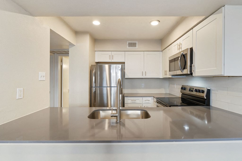 a kitchen with white cabinets and stainless steel appliances