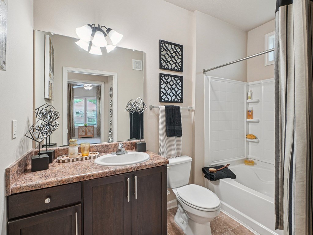 A bathroom with a brown granite countertop and white fixtures.