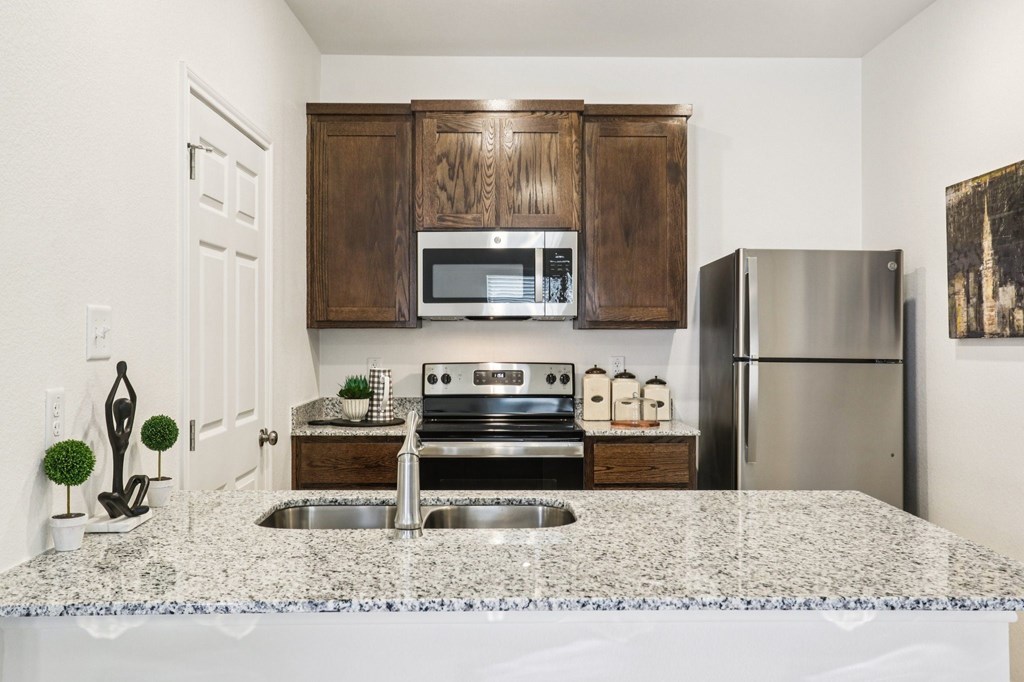 A kitchen with a granite countertop and stainless steel appliances.