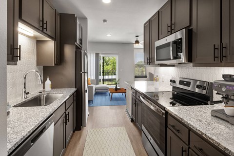 A modern kitchen with dark brown cabinets and a marble countertop.