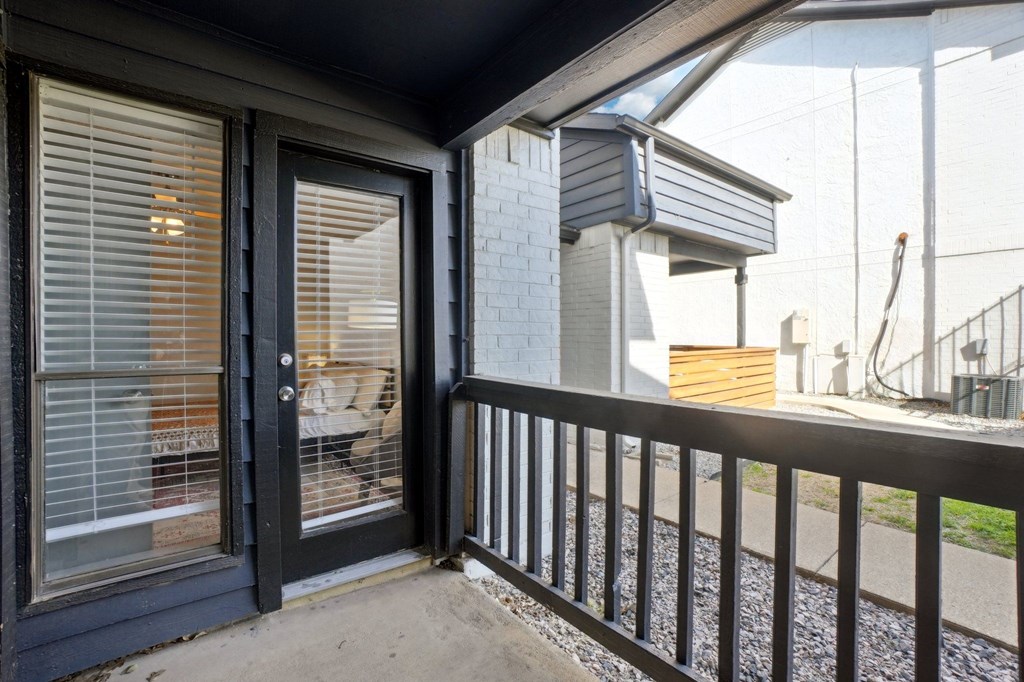 A black door with a glass window is on the left side of a white brick wall.