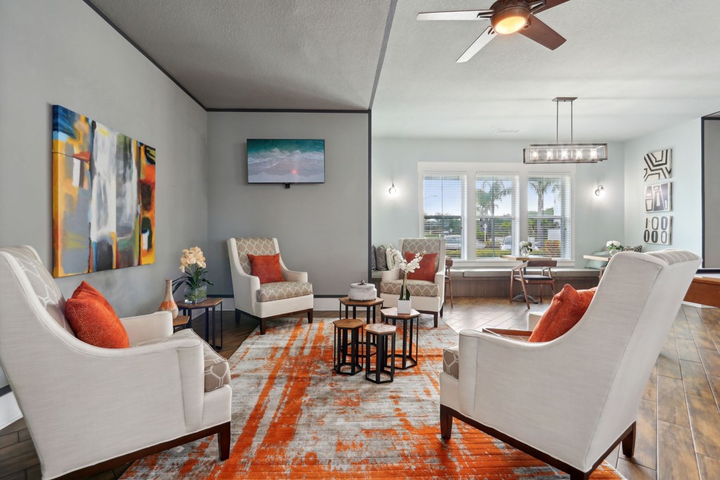 A living room with a white couch and orange pillow.